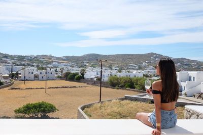 Rear view of woman with wineglass sitting on terrace