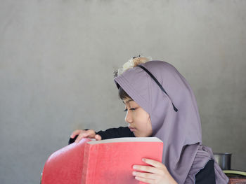 Cute muslim girl wearing hijab sleepy during reading book