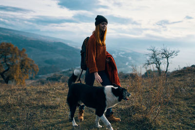 Man with dog standing by plants against sky