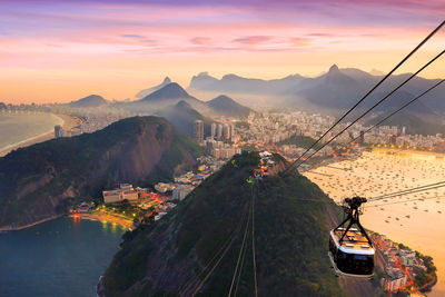 Overhead cable car and buildings against sky during sunset