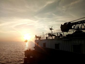 Silhouette ship on sea against sky during sunset