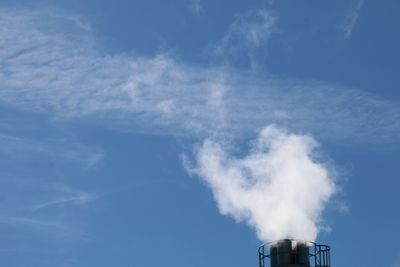 Low angle view of smoke emitting from chimney against sky