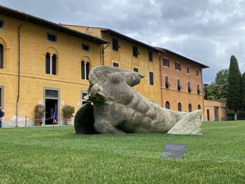 Statue by building against sky