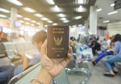 Cropped hand of woman holding passport at airport