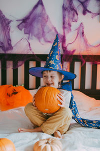 Little preschooler boy in festive halloween costume with a pumpkin lantern jack at home