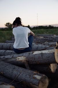 Rear view of woman sitting on wood