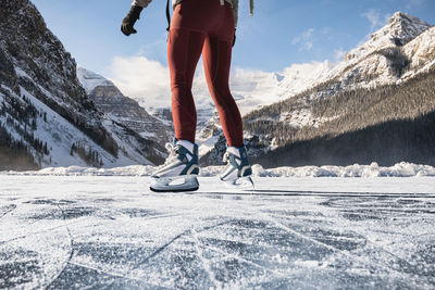 Young woman skating on frozen lake louise during cold winter day