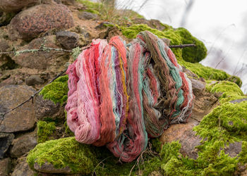 Stones overgrown with green moss, colored wool yarn skeins, handicraft concept, handicrafts
