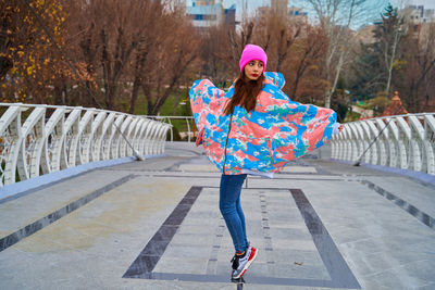 Full length portrait of happy woman standing on umbrella