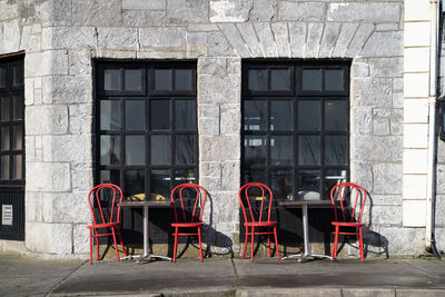 Empty chairs and tables against building