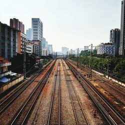 Railway tracks in city against clear sky