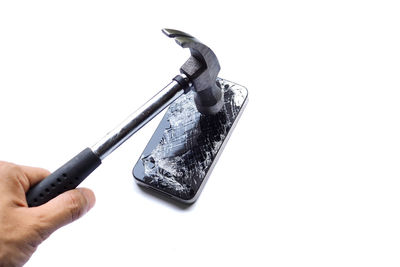 Close-up of hand holding mobile over white background