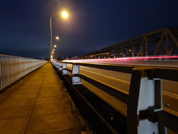 Illuminated light trails on bridge against sky at night