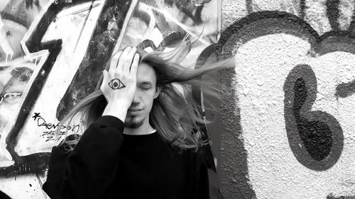 Portrait of young woman standing against graffiti wall