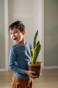 A boy holds a flower pot with sansevieria.