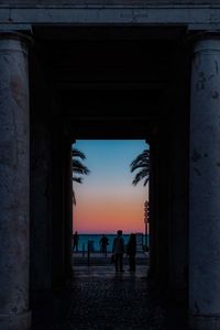 People at beach against sky during sunset