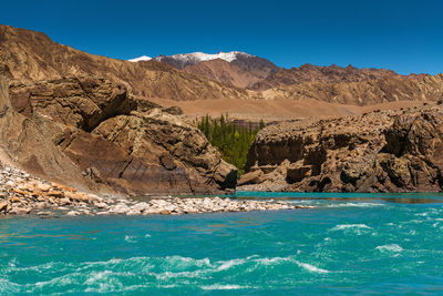 Scenic view of sea and mountains against clear sky
