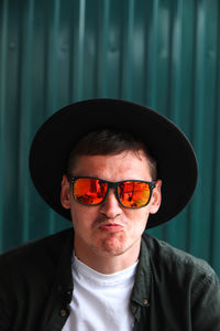 Portrait of young man wearing sunglasses against wall