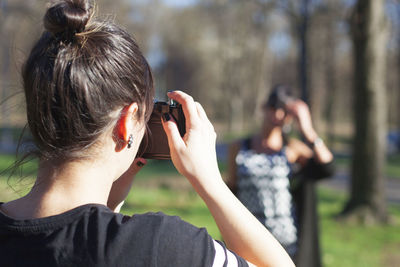 Rear view of woman photographing friend