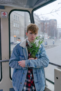 Decorative home palm tree, home flowers, a young guy holding a flower in his hands, traveling 