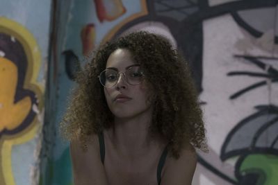 Portrait of young woman against graffiti wall