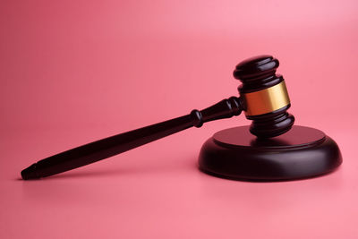 Close-up of electric lamp on table against pink background