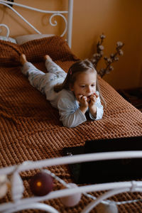 Child watching cartoons on laptop. serious kid with technology at home on bed spending time on-line