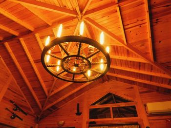 Low angle view of illuminated light bulb hanging on ceiling