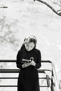 Portrait of young woman reading book on street