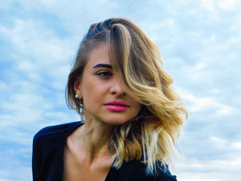 Low angle view of beautiful young woman against cloudy sky