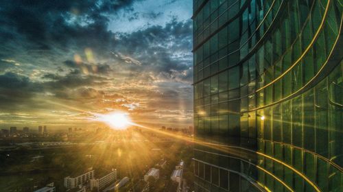 Digital composite image of modern buildings against sky during sunset