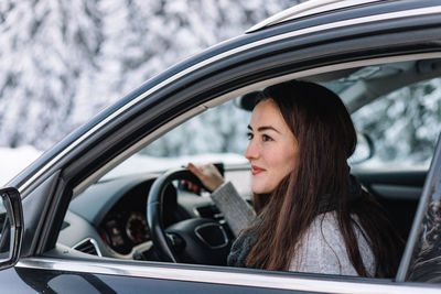 Woman driving in winter in a moutain area, while on road trip.