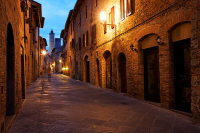 Illuminated alley amidst buildings in town at dusk