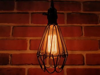 Close-up of illuminated light bulb against brick wall