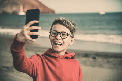 Portrait of smiling man using mobile phone at beach