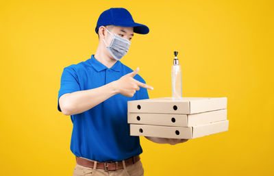 Man holding umbrella against yellow wall