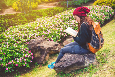 Woman reading book while sitting on stone