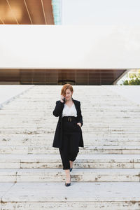 Full length portrait of woman standing against wall