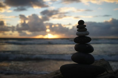 Stack of stones on beach during sunset