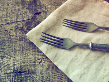 Close-up of forks with napkin on wooden table