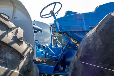 Close-up of machine part by car against sky