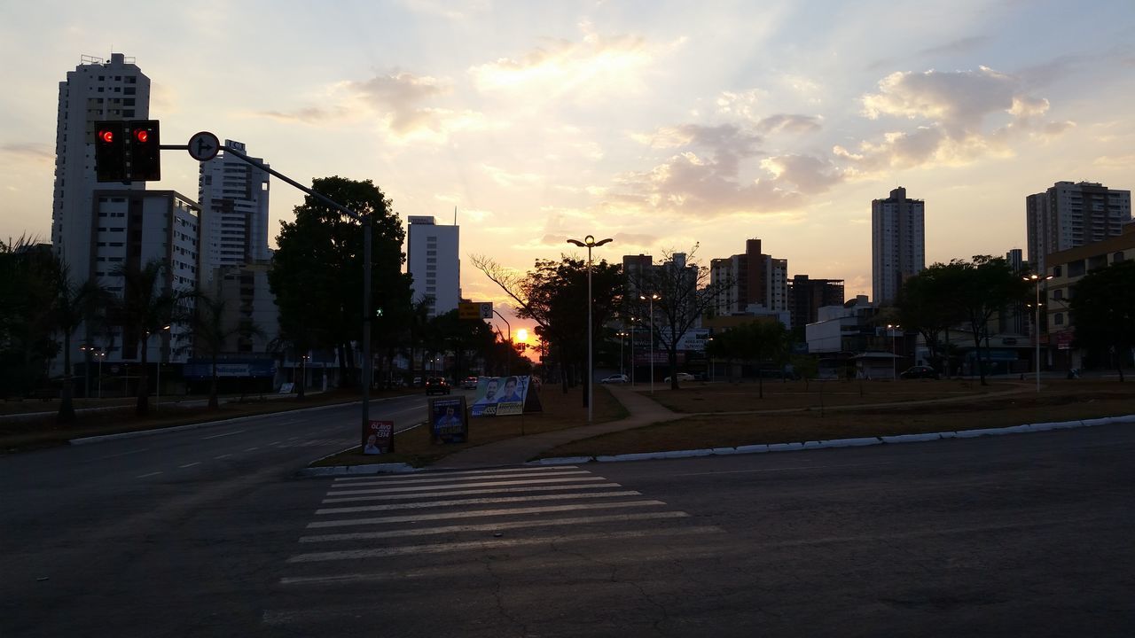 building exterior, architecture, built structure, city, sky, street, transportation, road, sunset, car, road marking, city life, skyscraper, cloud - sky, the way forward, building, office building, city street, land vehicle, tower