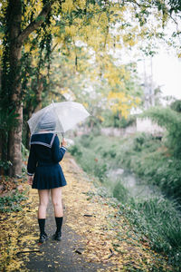 Full length of woman with umbrella walking in rain