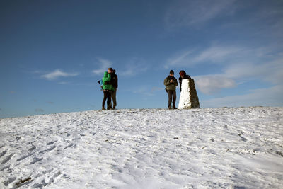 Rear view of people on snow covered land against sky