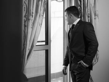 Side view of young man looking through window