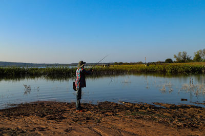 The man standing in lake against clear sky