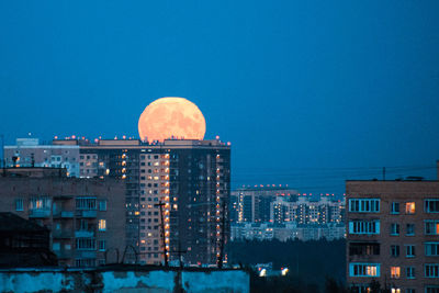 Illuminated buildings against blue sky at dusk