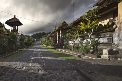 Empty road amidst buildings against sky