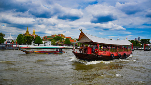 View of boats in river against cloudy sky