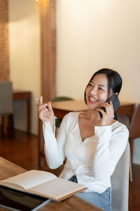 Young woman using mobile phone while sitting at home